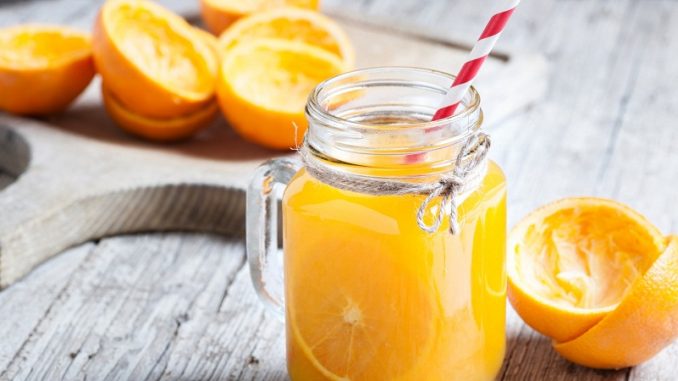 juice of Orange squeezed in container of glass on table of wood